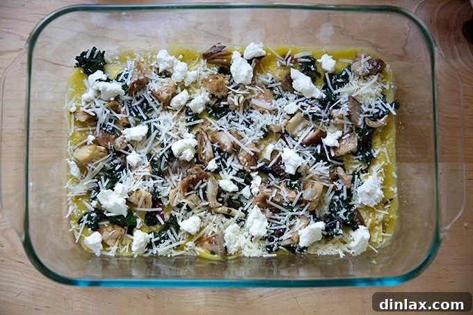 Effortless Butternut Squash Lasagna with Hearty Greens and Mushrooms 14 A tempting layer of grated Parmesan and mozzarella cheese generously scattered over the vegetables and sauce, completing a delicious tier of the lasagna.