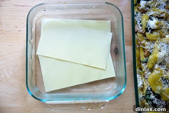 Effortless Butternut Squash Lasagna with Hearty Greens and Mushrooms 16 Three no-boil lasagna noodles carefully soaking in a shallow dish filled with hot water, preparing them for the top layer of the lasagna.