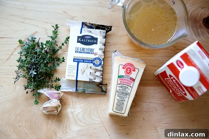 Various ingredients for potato gratin laid out on a clean countertop, including fresh thyme, garlic, cheeses, and liquids.