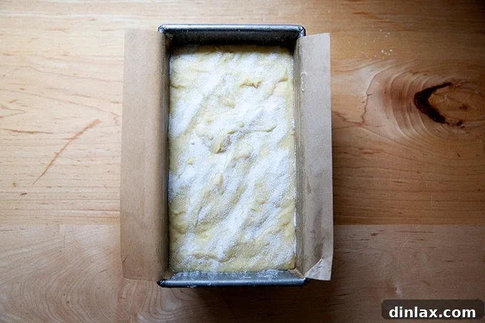 An unbaked pound cake batter, smoothed and topped with granulated sugar, sitting in a loaf pan, poised for baking.
