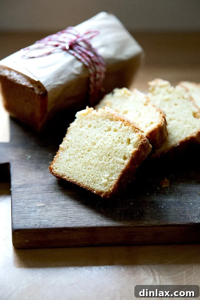 A perfectly sliced loaf of pound cake revealing its dense, moist crumb, resting on a rustic wooden board.