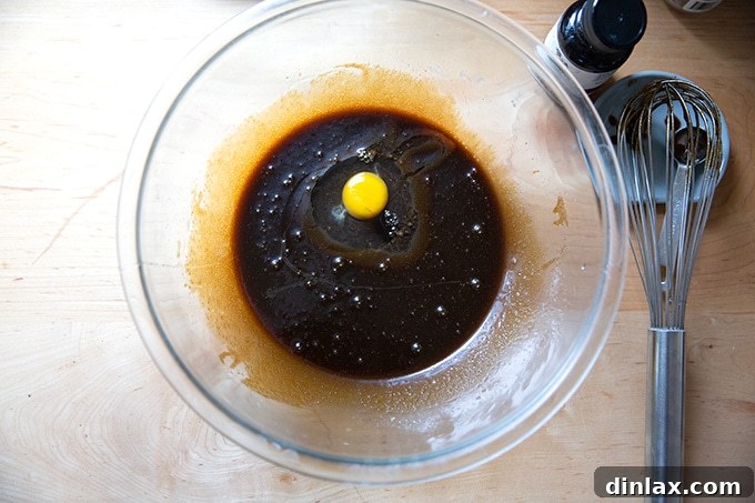 A bowl of gingersnap cookie batter with a single egg added, partially mixed.