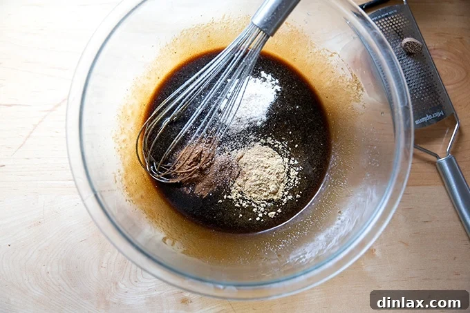 A bowl of fully mixed wet ingredients for gingersnap cookies, including spices and baking soda.