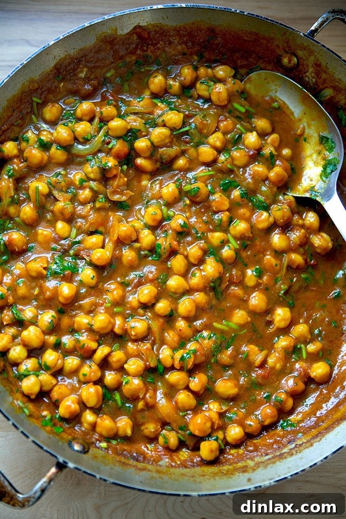 A skillet brimming with perfectly cooked, aromatic curried Thai chickpeas, showcasing their rich texture and vibrant colors, ready to be served.