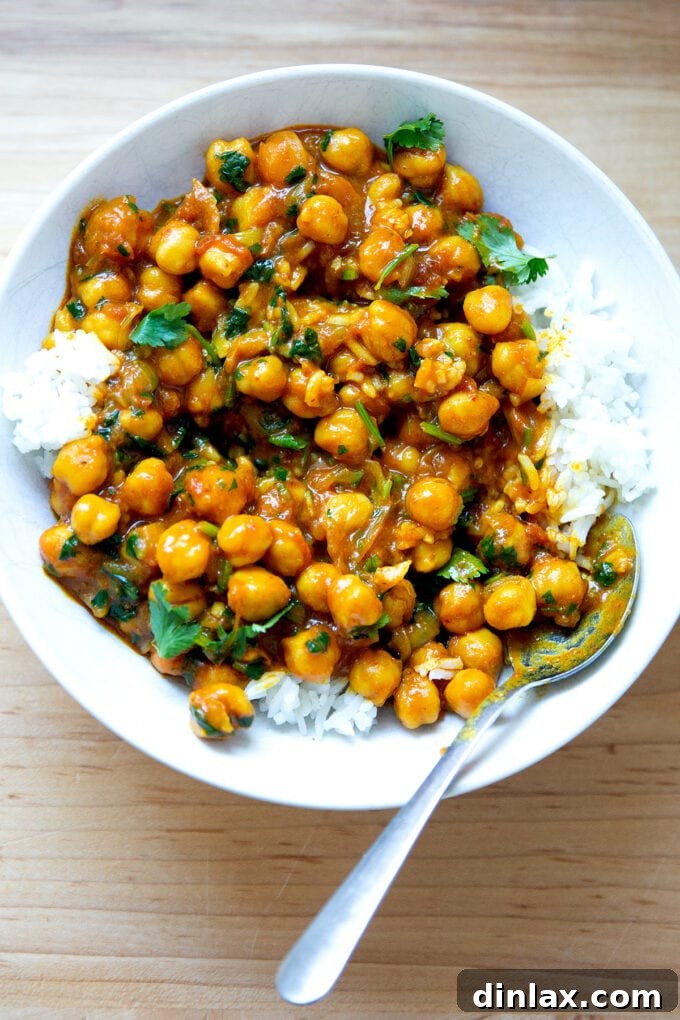 A beautifully presented bowl of creamy curried Thai chickpeas nestled beside a mound of fluffy white rice, garnished with fresh herbs, ready for a delightful meal.