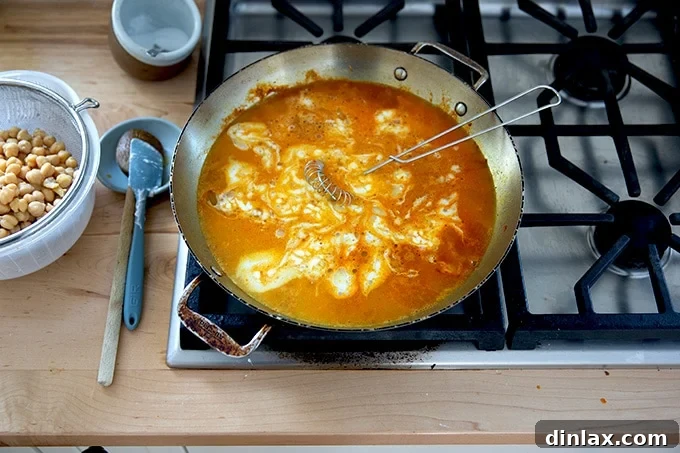 The simmering skillet on the stovetop, showing the curried Thai chickpea mixture after adding brown sugar, fish sauce, and salt, with ingredients harmoniously blending.