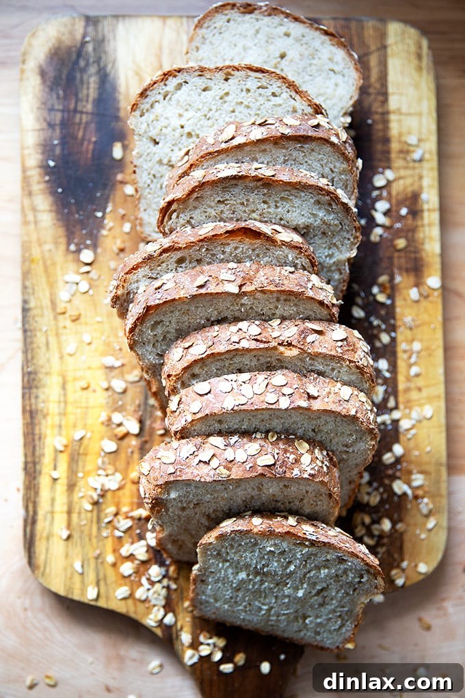 A cutting board laden with perfectly sliced no-knead maple oat bread, ready for serving.