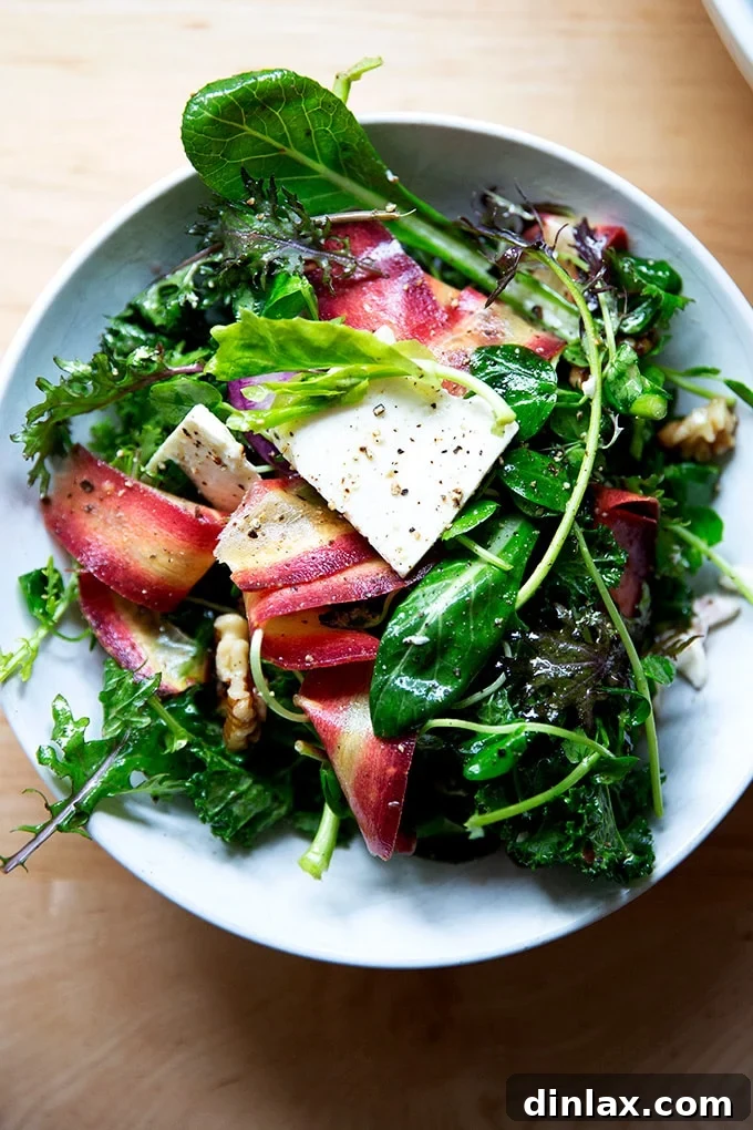 A vibrant spring salad in a large bowl, featuring mixed greens, radishes, carrots, feta, and walnuts.