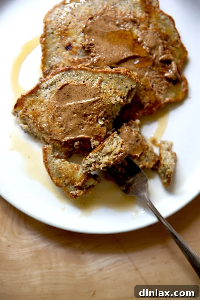Banana-oat pancakes on a plate with almond butter and maple syrup.