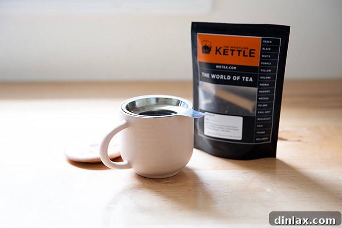 15 Perfect Mothers Day Gifts 21 A steaming cup of tea in a ceramic mug with an infuser, perfect for a relaxing moment.