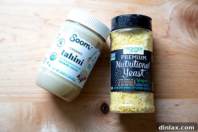 15 Perfect Mothers Day Gifts 6 A jar of tahini and a tub of nutritional yeast, essential vegan pantry items, on a countertop.