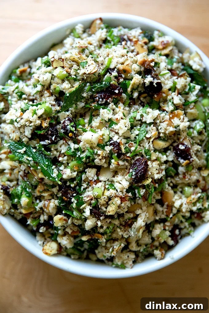 A vibrant bowl of cauliflower couscous salad, garnished with fresh herbs and toasted almonds.