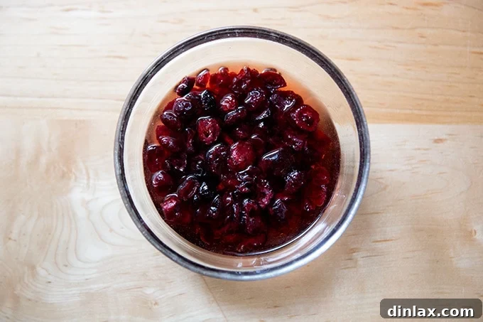 Dried cherries soaking in a small bowl with vinegar, a crucial step for plumping.