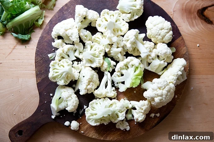 A cutting board with fresh cauliflower florets, prepped for processing.