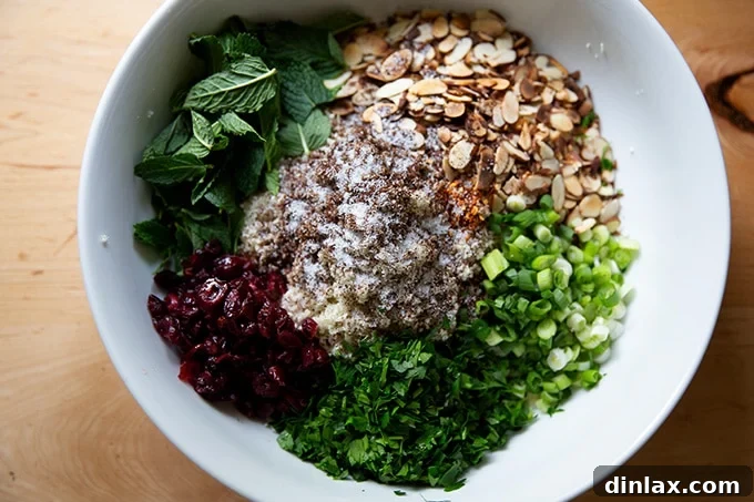 All the ingredients for the cauliflower couscous salad, except almonds and mint, combined in a bowl.
