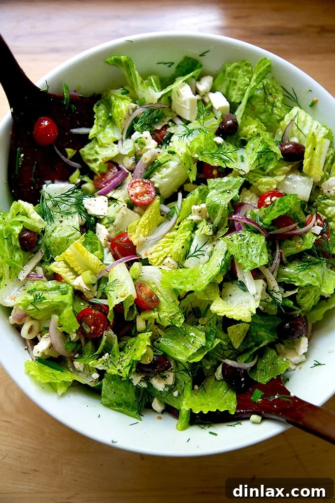 A large white bowl showcasing a perfectly tossed Greek salad, vibrant and ready to be served.