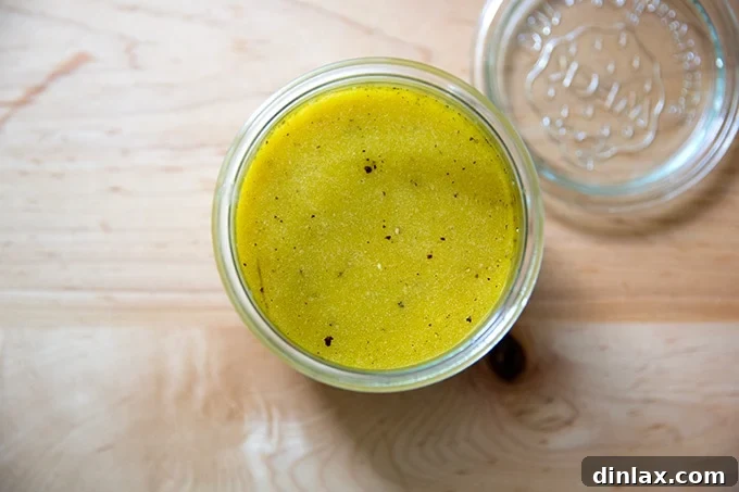 A clear glass jar filled with homemade Greek salad dressing, sitting invitingly on a countertop.