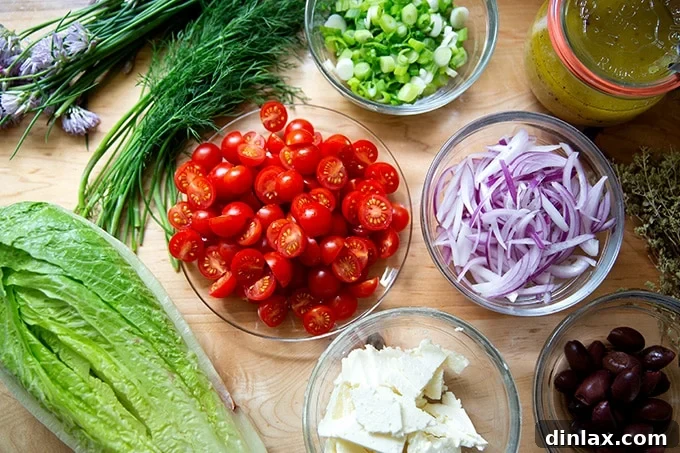 All the fresh ingredients required to make a traditional Greek salad are displayed on a pristine countertop.