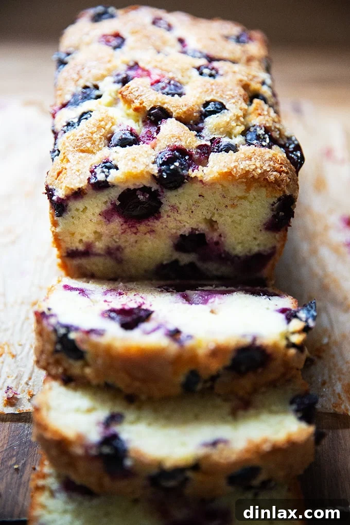 Effortless Lemon Blueberry Bread 19 A beautifully sliced lemon-blueberry quick bread, revealing its moist crumb and scattered blueberries, presented on a wooden cutting board.