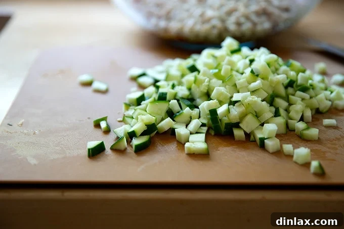 Finely diced zucchini pieces scattered on a wooden cutting board, ready for the salad.
