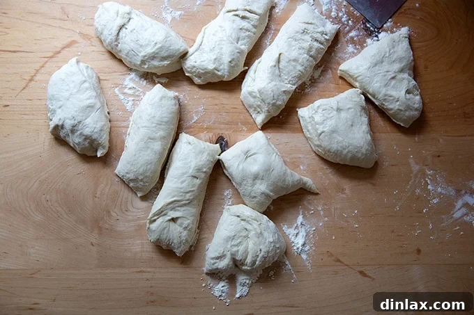 Ten evenly divided portions of pretzel roll dough on a work surface.