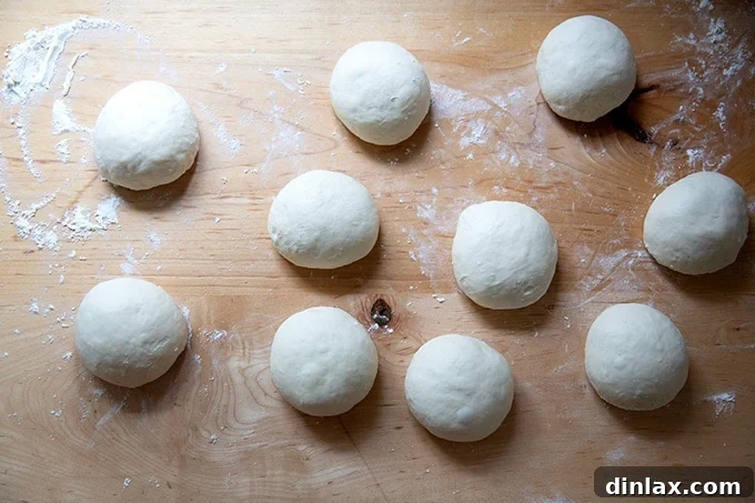 Ten perfectly balled pretzel roll dough portions ready for proofing.