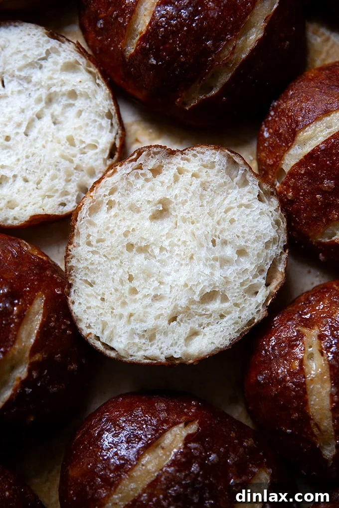 A freshly baked pretzel roll, perfectly halved to reveal its soft, airy interior.