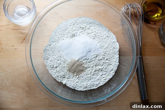 A large bowl containing flour, salt, sugar, and instant yeast, ready for liquids.