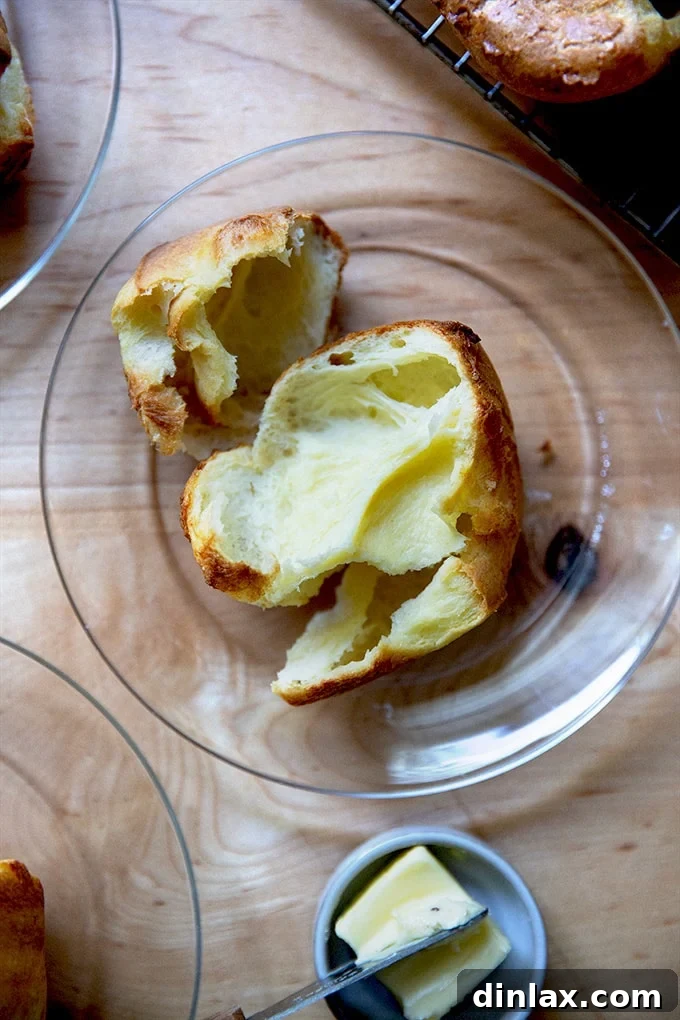 A popover on a plate, with a knife and butter nearby.