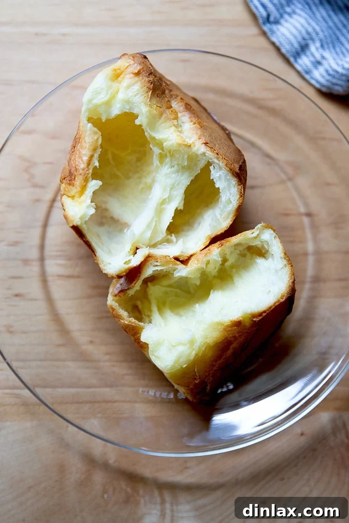 A halved popover on a plate, revealing its airy and custardy interior.