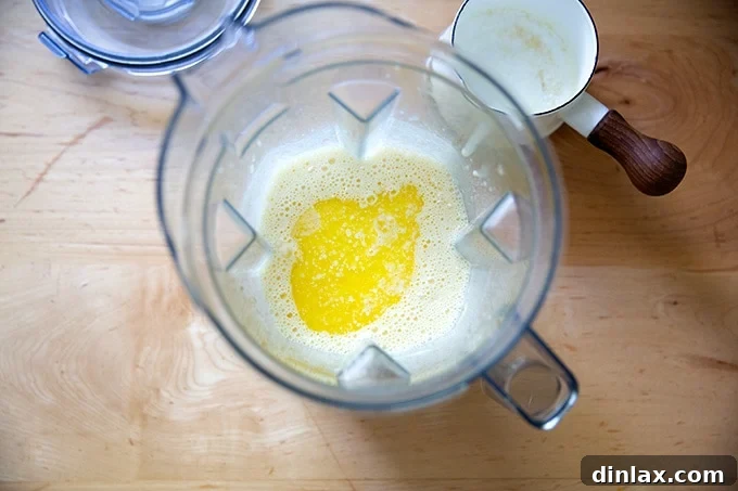 Melted butter being poured into a blender with popover batter.