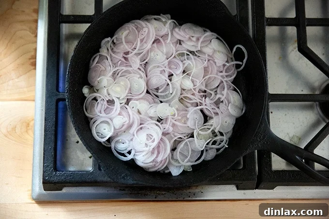 Golden Roasted Green Beans with Sweet Shallot Glaze 7 Shallots in a cast iron skillet on the stovetop.