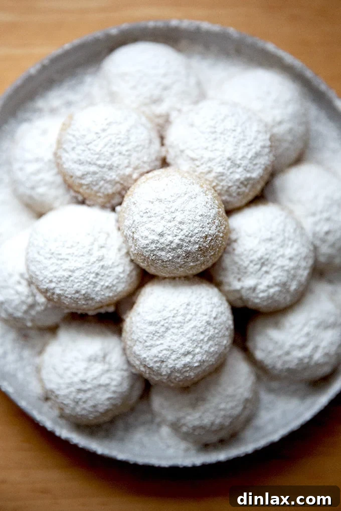 A beautifully arranged plate of lemon-almond snowball cookies dusted with powdered sugar, ready to be enjoyed.