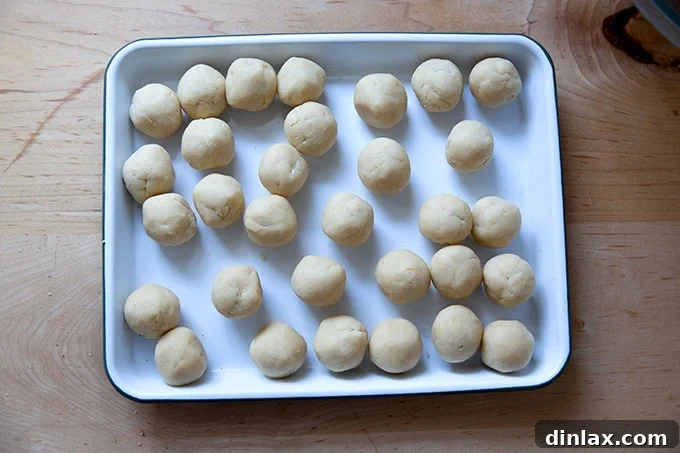 A tray of perfectly rolled lemon-almond snowball cookie dough balls, smooth and round, ready for baking.