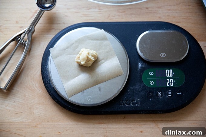 A kitchen scale precisely weighing a 20-gram portion of lemon-almond snowball cookie dough.