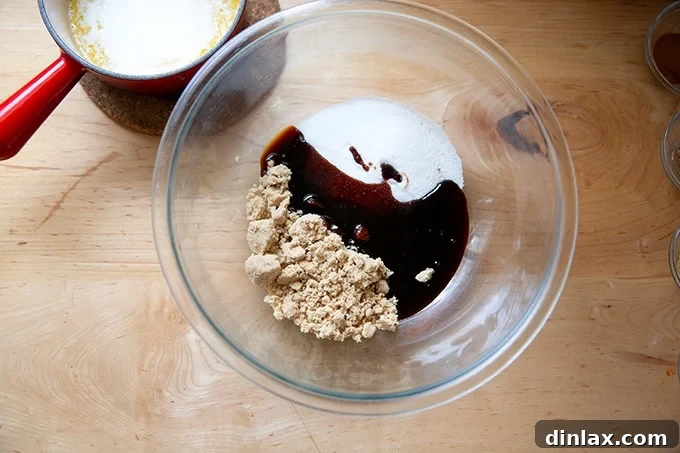 Perfectly Imperfect Gingerbread Cookie Bars 5 A large mixing bowl containing a rich mixture of brown sugar, white granulated sugar, and dark, viscous molasses.