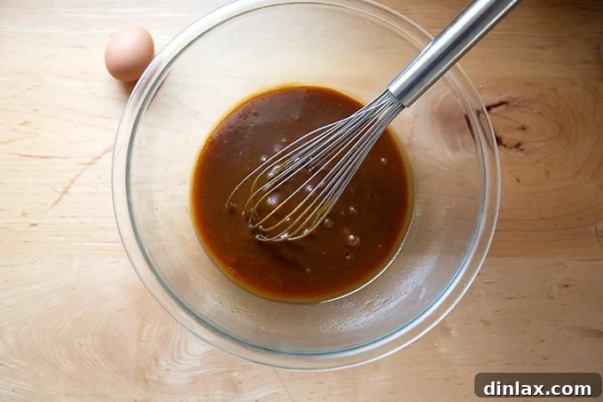 Perfectly Imperfect Gingerbread Cookie Bars 7 A whisked mixture of sugars, melted butter, and molasses in a large bowl, with a single egg waiting to be added.