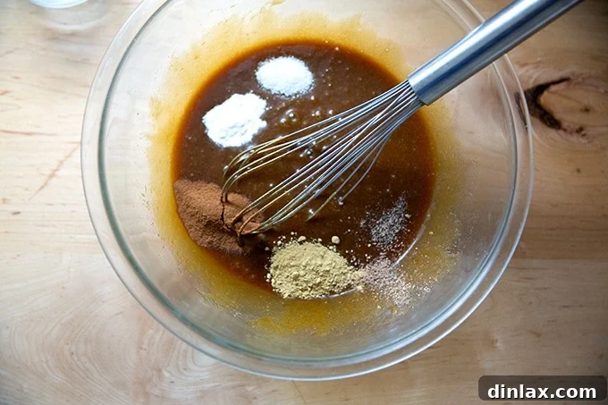 Perfectly Imperfect Gingerbread Cookie Bars 9 A bowl containing the combined wet ingredients, now with added baking soda, cinnamon, ginger, nutmeg, and salt, ready for a final whisk.