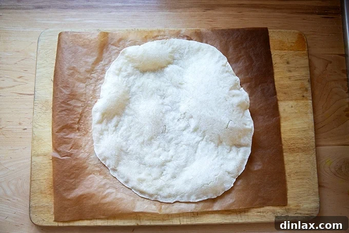 A parbaked gluten-free pizza crust, fresh out of the oven, resting on a cutting board.