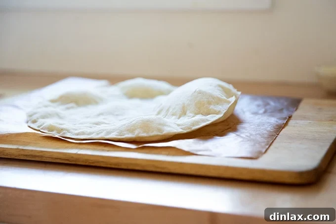 Side view of a parbaked gluten-free pizza crust, showing slight puffing which should be gently deflated.