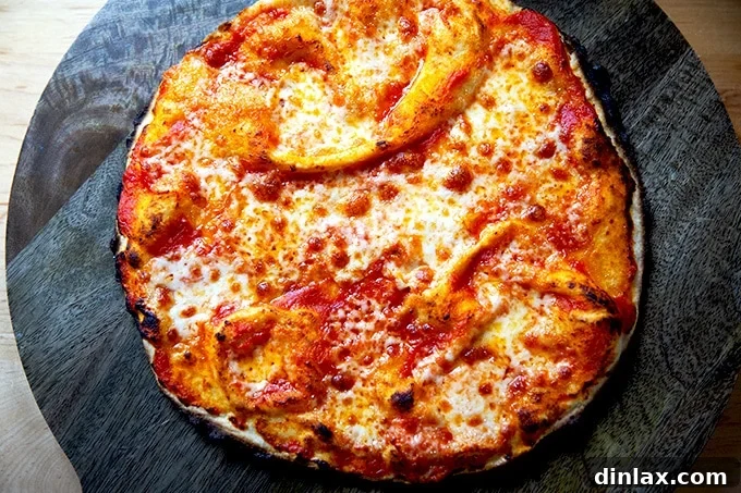 A freshly baked gluten-free Margherita pizza, golden and bubbly, on a wooden cutting board.