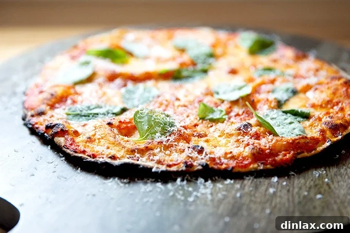 Side view of a freshly baked, gluten-free Margherita pizza adorned with fresh basil, on a cutting board.