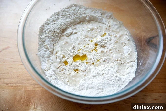 Wet ingredients (water and olive oil) being added to the dry ingredients for gluten-free pizza dough.