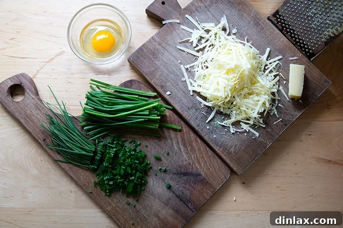 Light and Delicate Gluten Free Buckwheat Crepes 17 Two wooden cutting boards displaying a pile of grated Gruyere cheese and a mound of chopped chives, alongside a small bowl holding a fresh egg, all ready for the galette preparation.