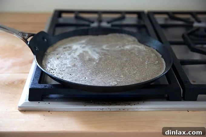Light and Delicate Gluten Free Buckwheat Crepes 10 Buckwheat crepe batter just poured into a nonstick skillet, spreading to form a thin, even layer as it begins to cook.
