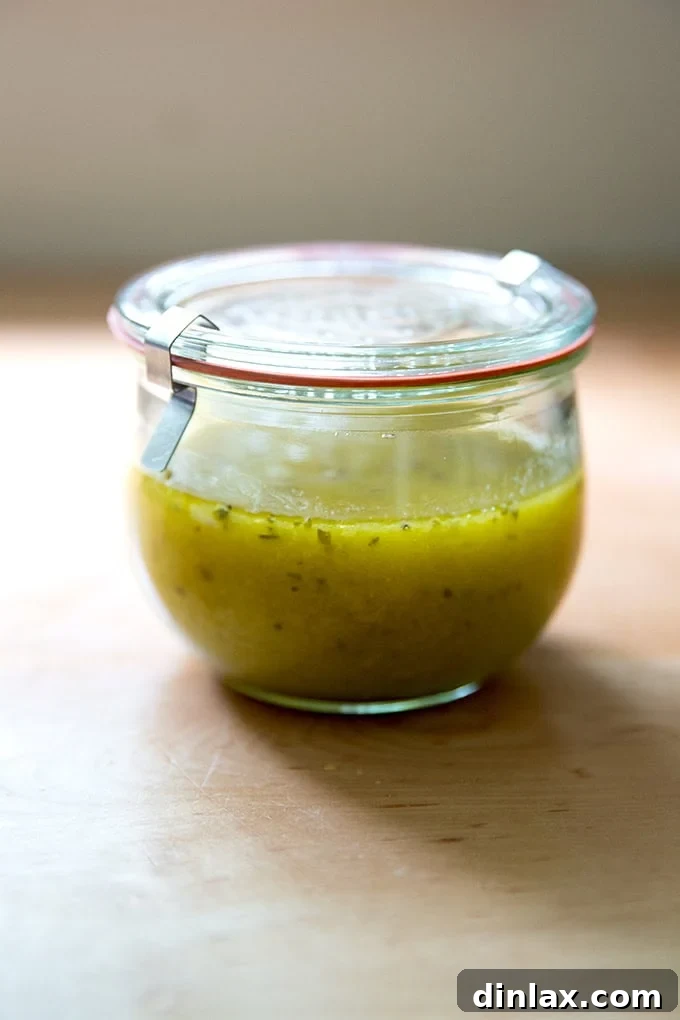 A beautiful Weck jar filled with golden homemade Italian dressing, ready to be poured over a fresh salad.