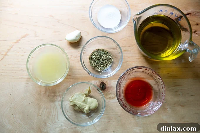 All the measured ingredients for Italian dressing, neatly presented in small bowls and measuring cups on a clean countertop.
