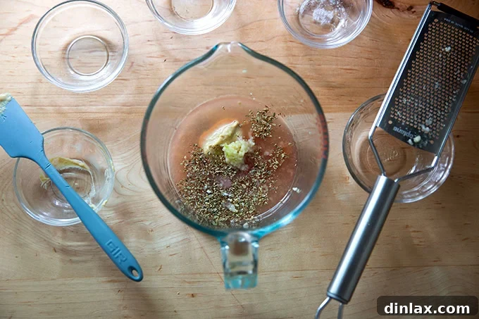 The non-oil ingredients for Italian dressing – red wine vinegar, lemon juice, mustard, garlic, oregano, salt, and sugar – gathered in a 4-cup liquid measuring cup.