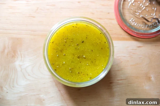 An overhead shot of a clear Weck jar, perfectly filled with the golden, emulsified homemade Italian dressing.