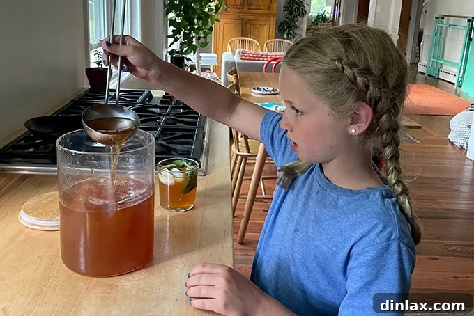 A young girl, Tig, joyfully ladling homemade iced tea into a glass filled with ice, ready to serve.